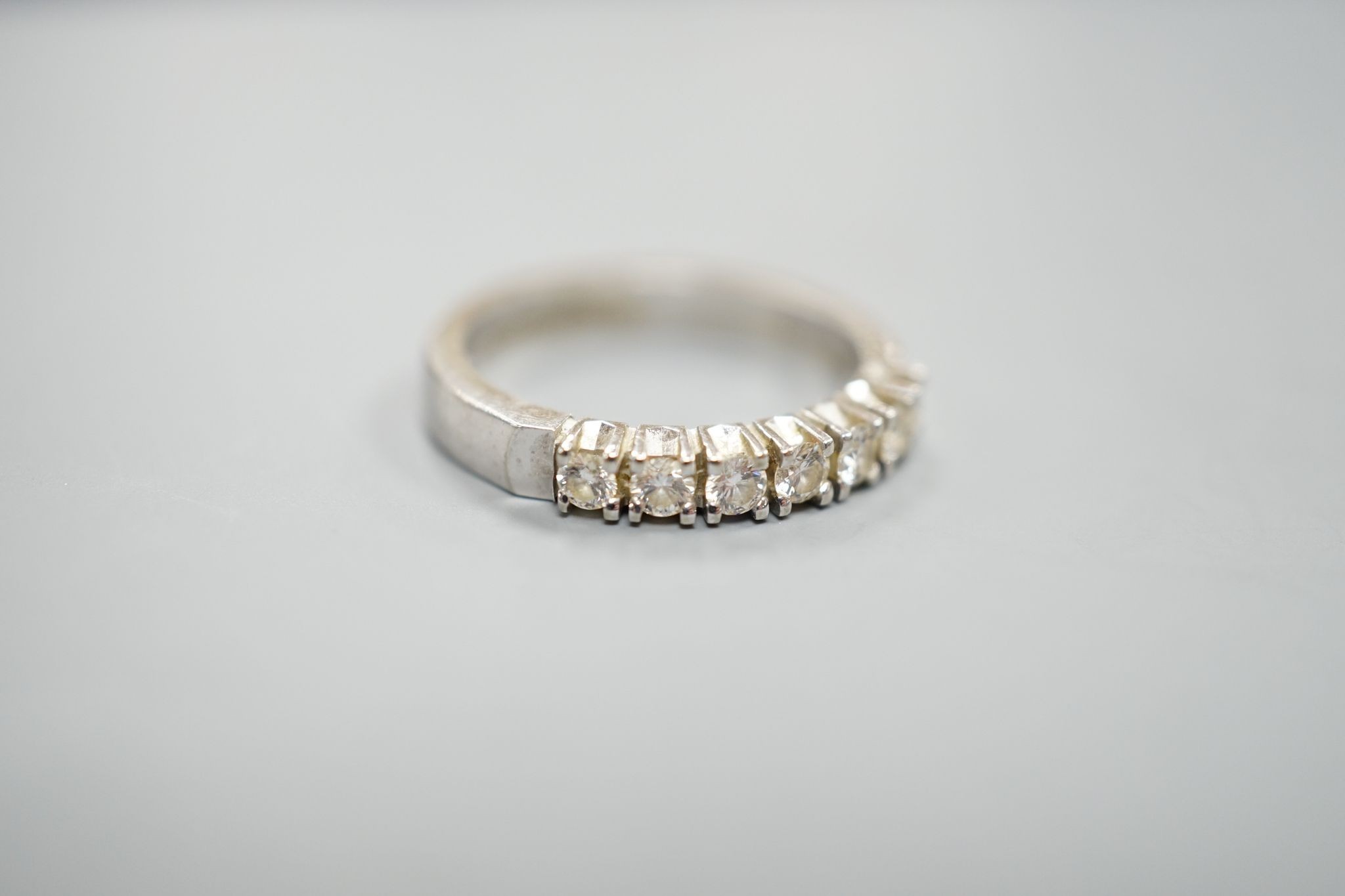 A modern 18k white metal and seven stone diamond set half eternity ring, size M, gross weight 4.4. grams.